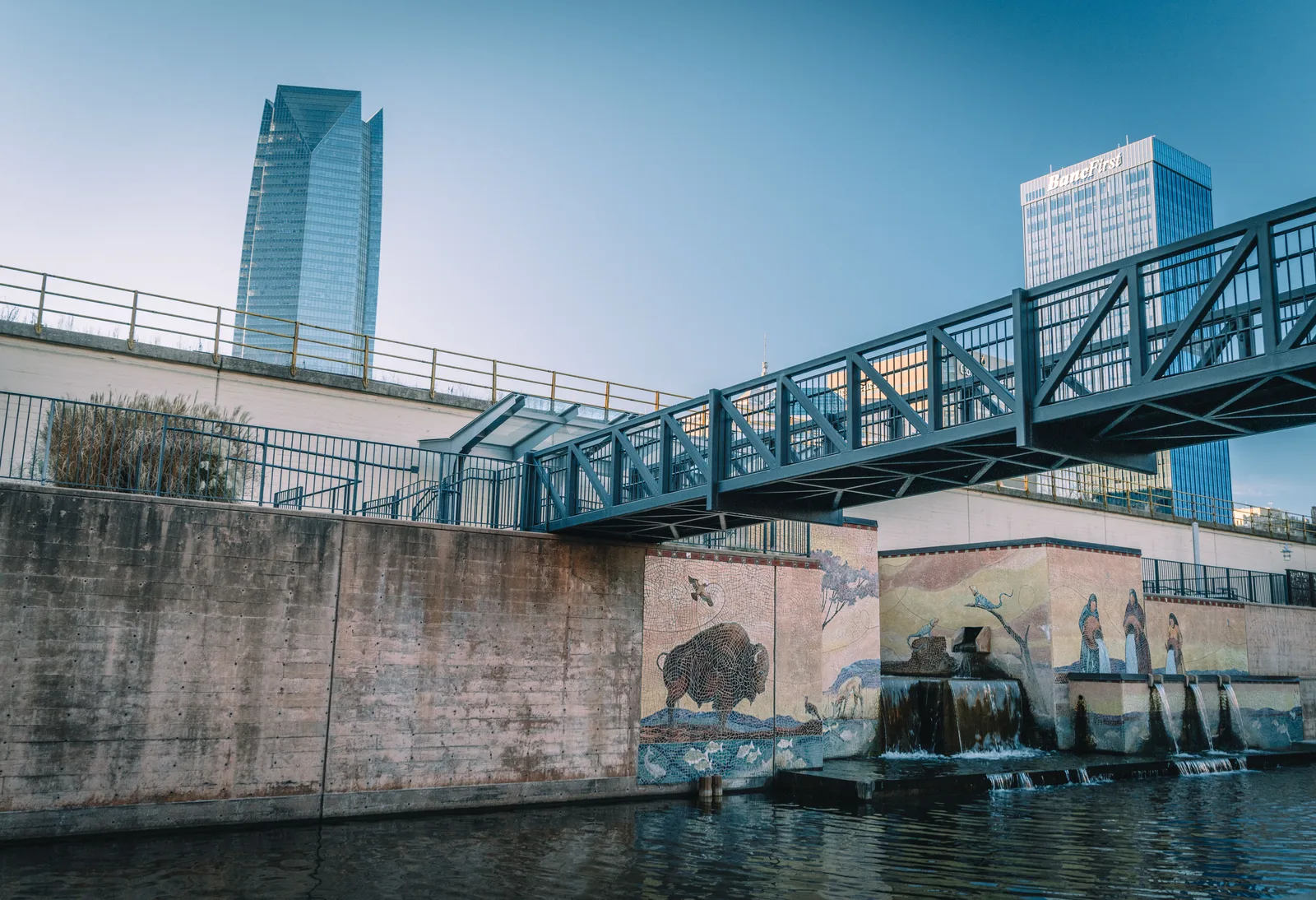 Canal walkway and footbridge below downtown towers in Oklahoma City