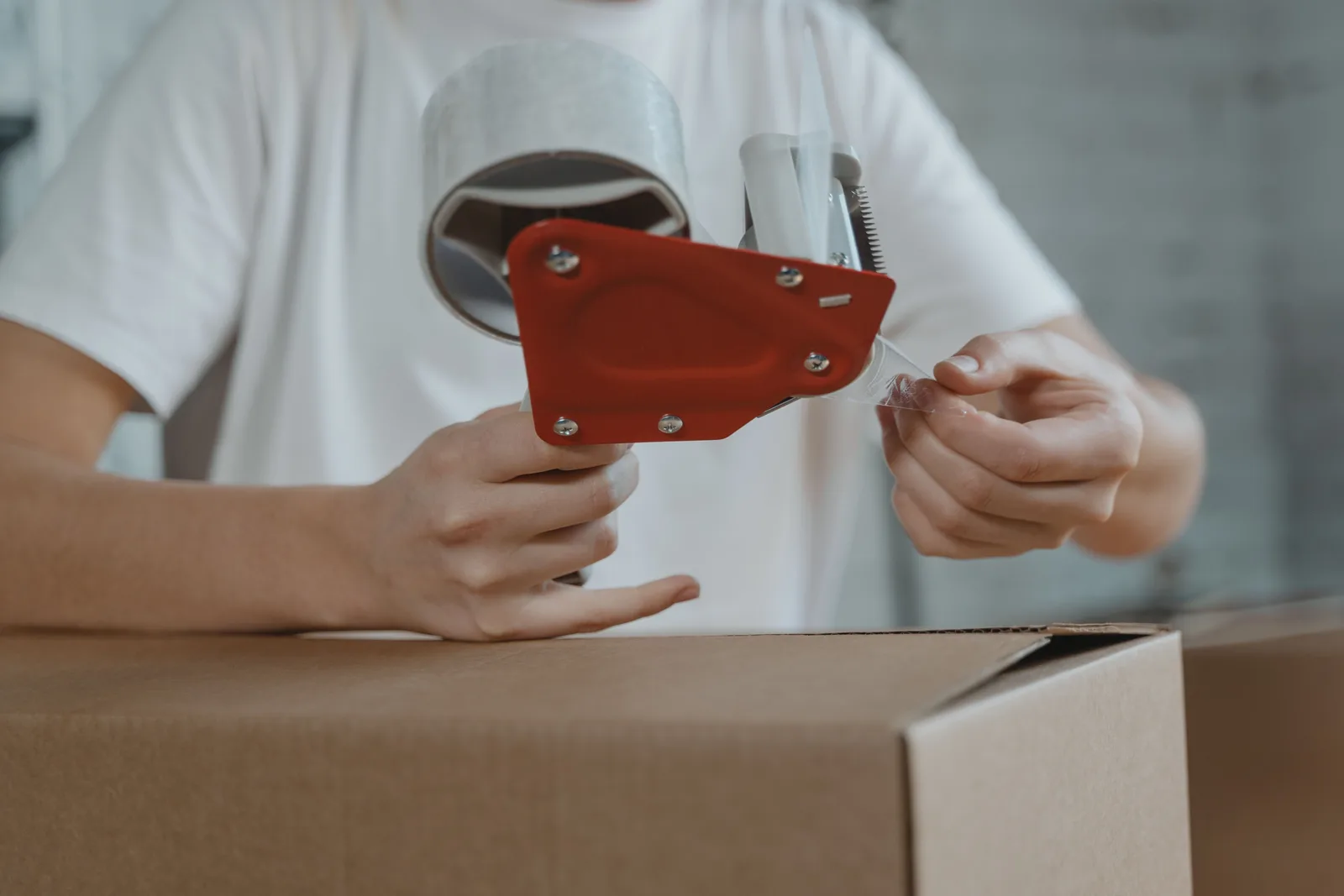 Close up of a tape dispenser sealing a cardboard carton