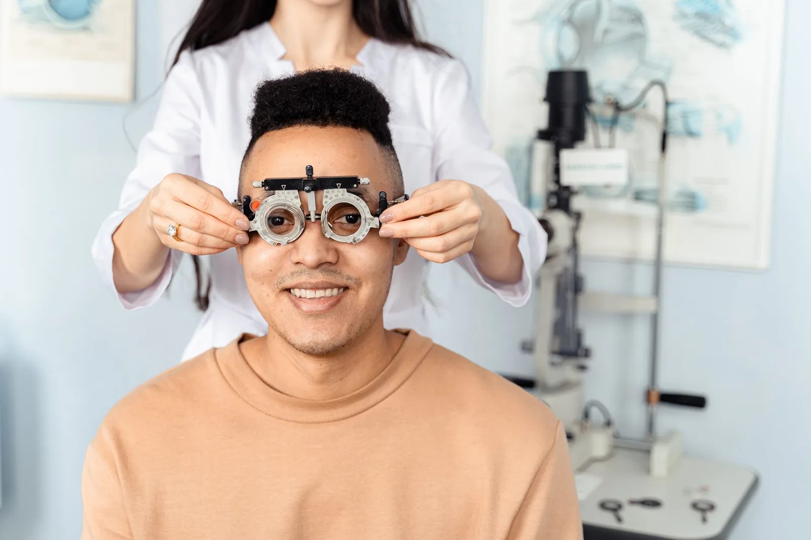 A patient wearing an optical trial frame while an optometrist adjusts the lenses
