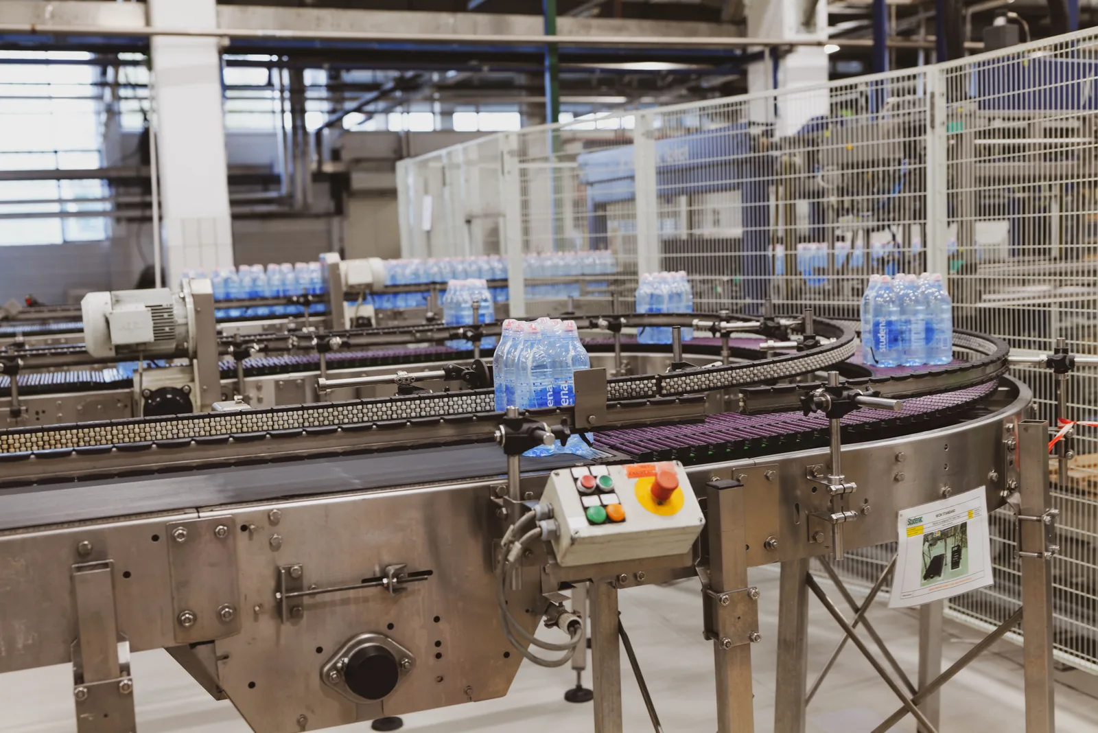 Bottles move along a stainless steel conveyor inside a bottling plant.