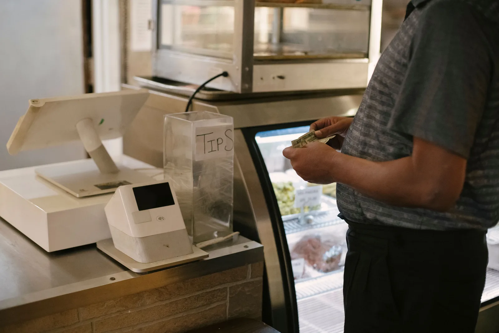 A customer paying cash at a grocery store register