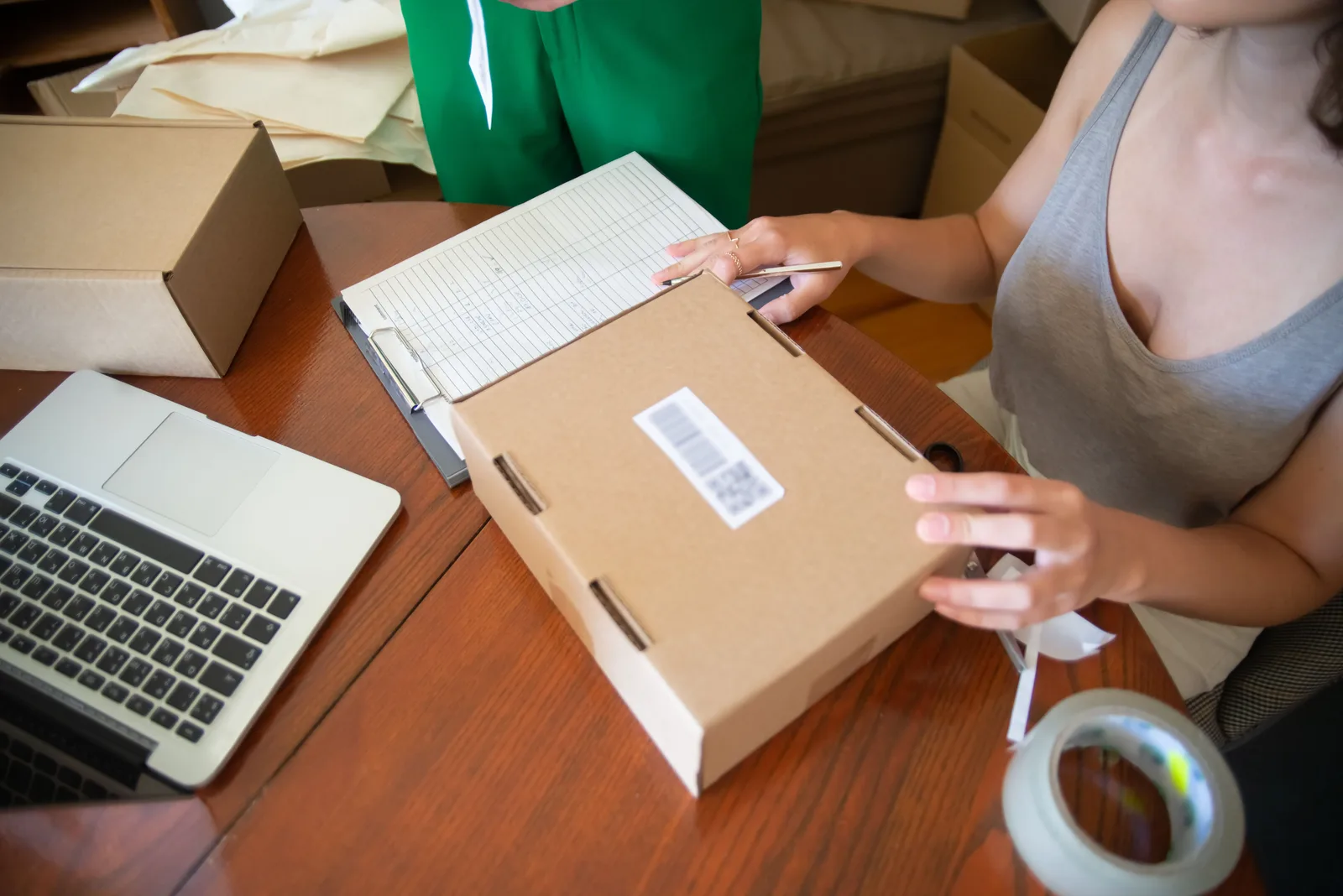 Two people taping and labeling customer orders into cardboard boxes at a work table