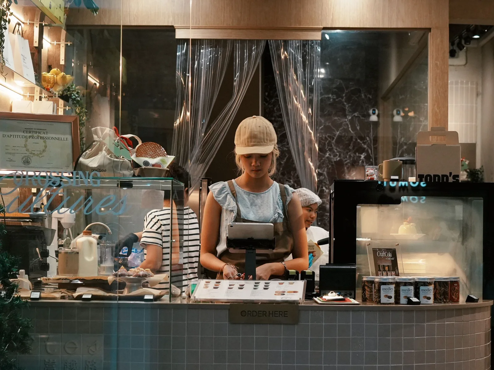 Staff working behind a bakery service counter, taking an order at the point of sale terminal