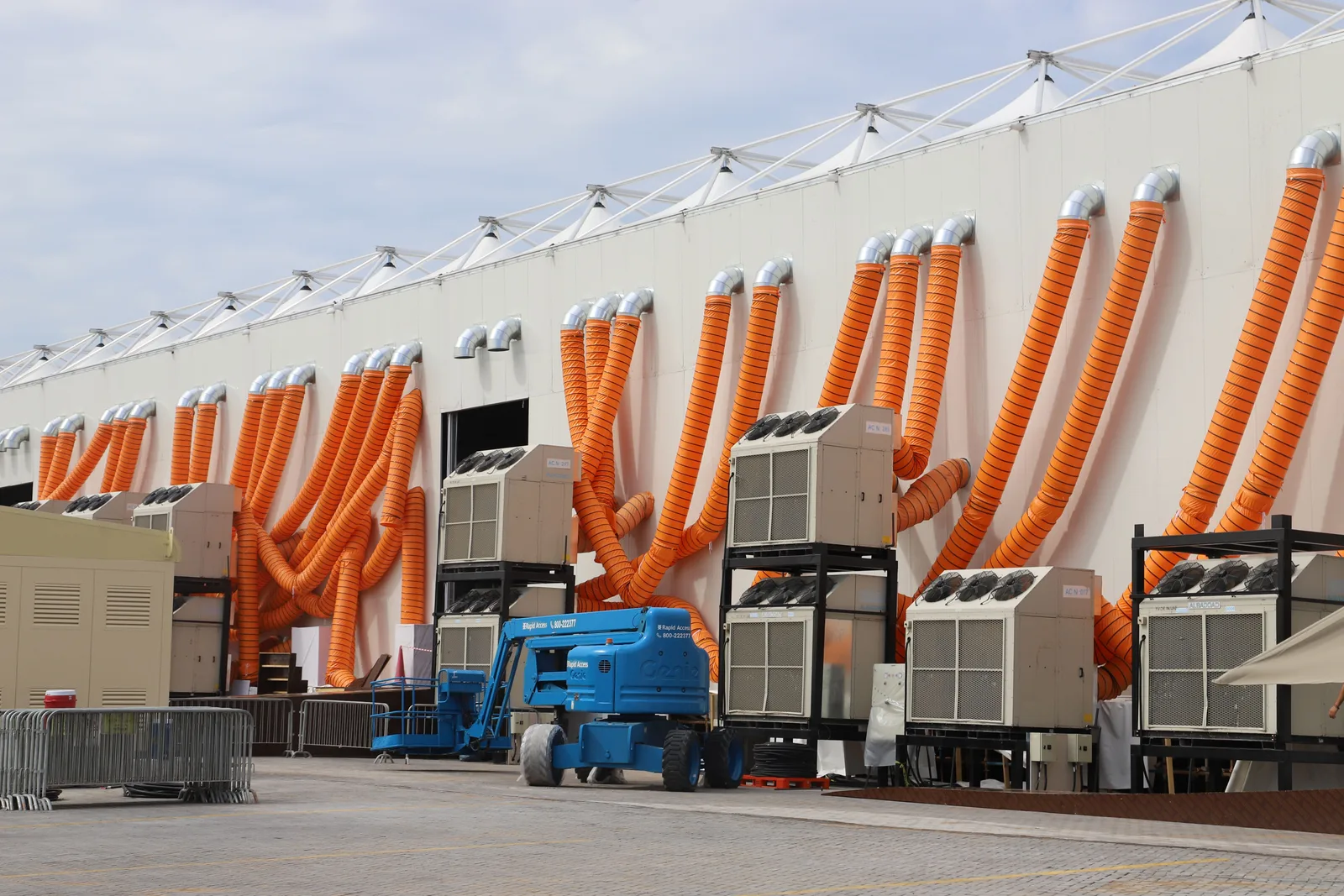 Modern industrial cooling units connected to bright orange ducting on the outside of a building