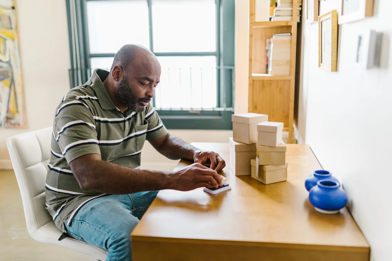Vendedor sellando y preparando pequeños paquetes en un escritorio dentro de una oficina en casa