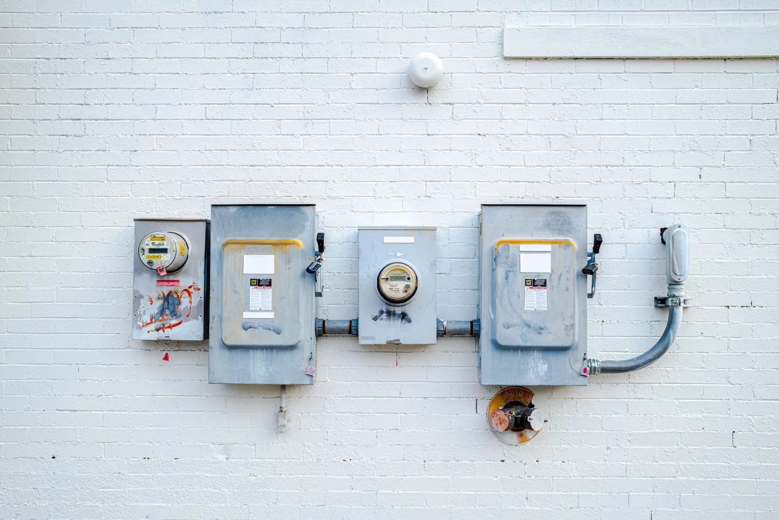Medidores eléctricos y cajas de desconexión de servicio montadas en una pared de ladrillo blanco