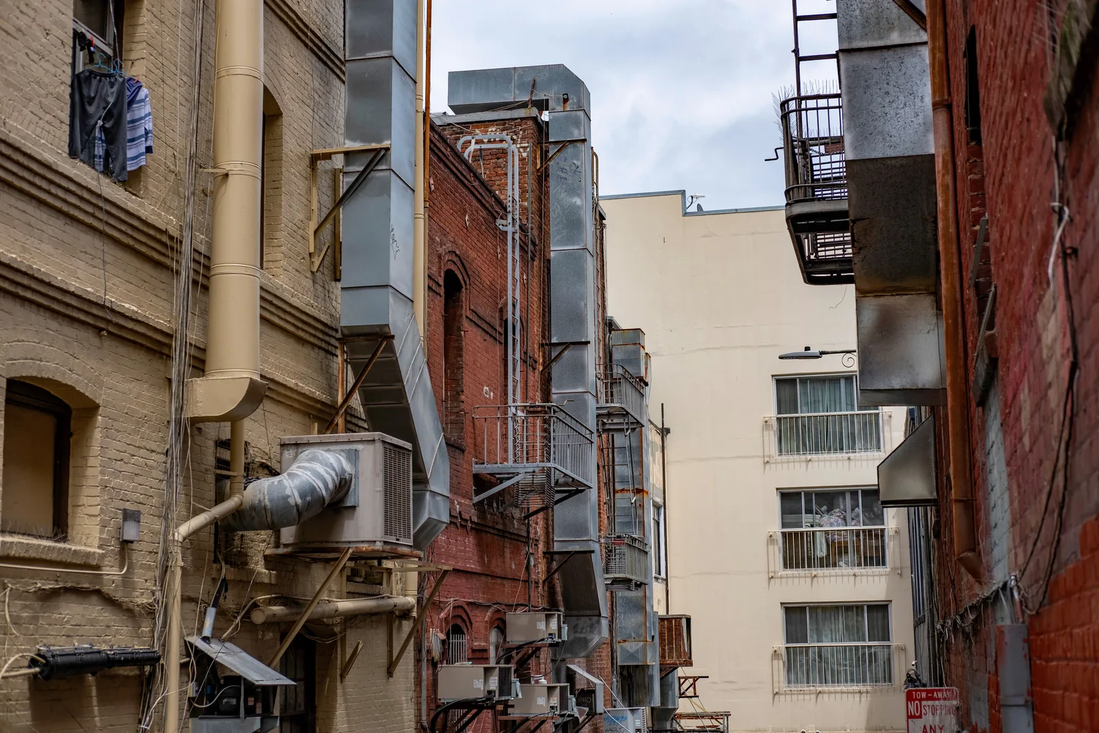 Exterior ductwork, condensers and ventilation runs covering the walls of buildings along a city alley