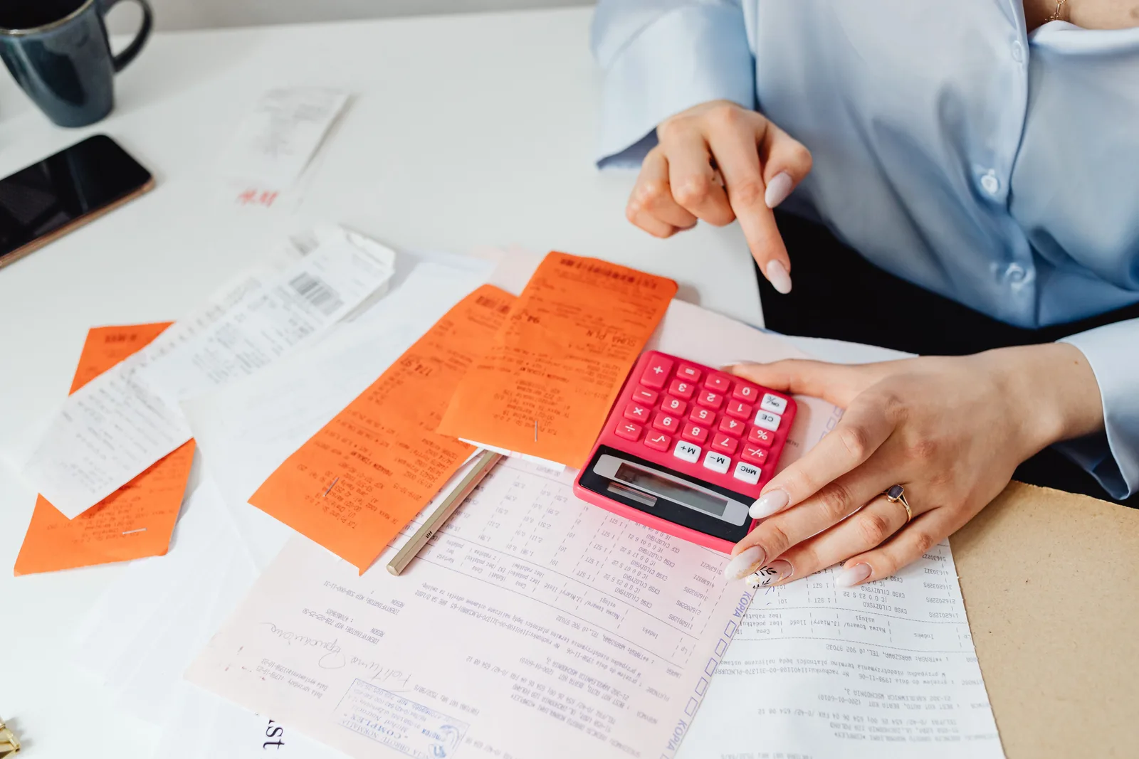 Working through a stack of receipts with a calculator at a desk