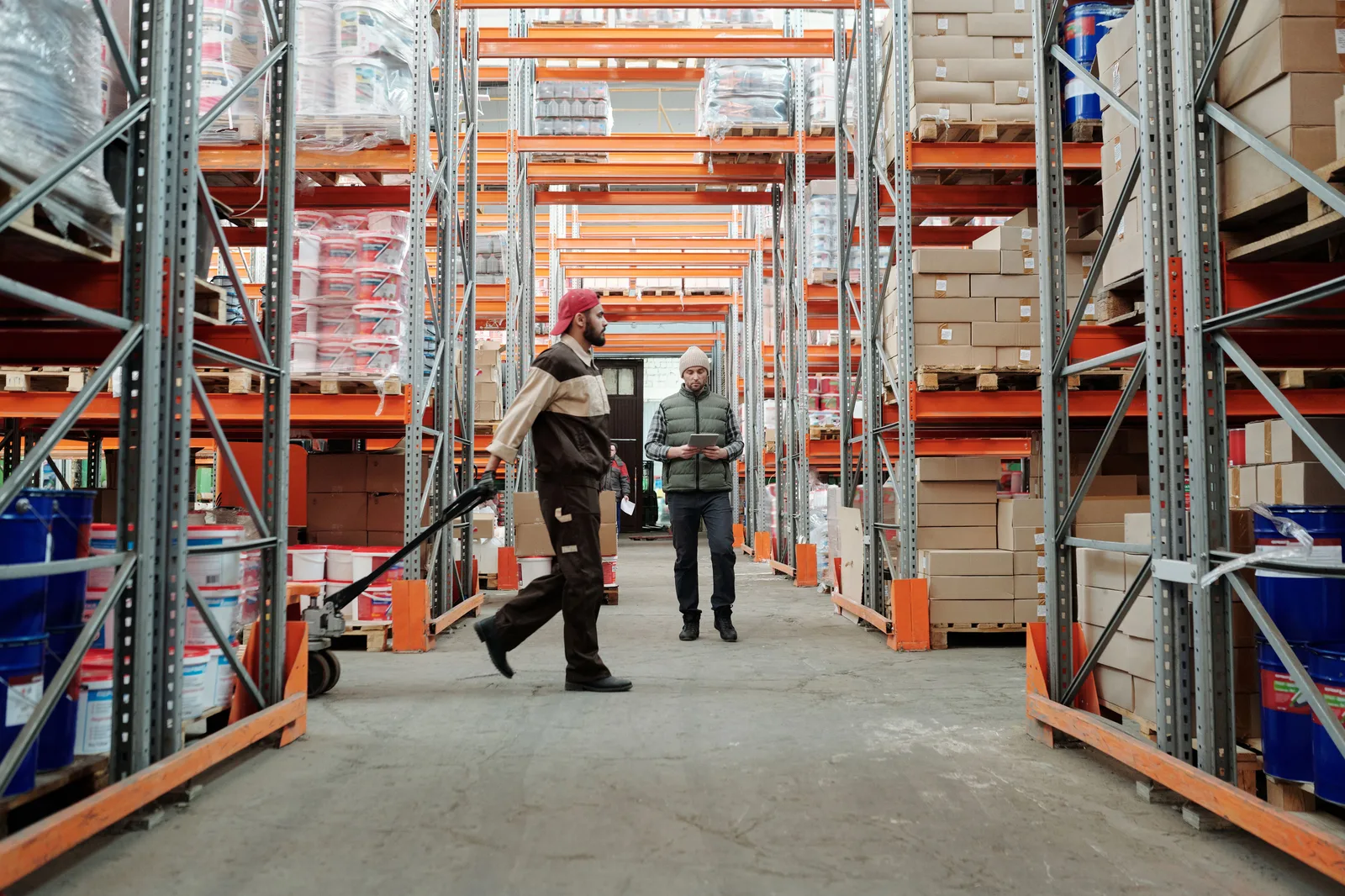A warehouse aisle of racked stock with staff working